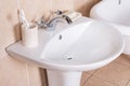 Closeup of a white bathroom sink with a shiny modern faucet, soap, and toothbrushes Royalty Free Stock Photo