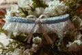 Closeup of a white and blue garter on a bouquet with blurred background