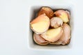 Closeup of a white bowl of pink garlic cloves