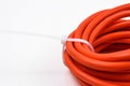 Closeup of a white cable tie tied to a roll of orange cable wire