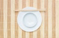 Closeup white ceramic chalice on circle dish and wood chopsticks on wood mat textured background on dining table in top view Royalty Free Stock Photo