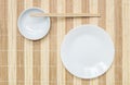 Closeup white ceramic dish and chalice with wood chopsticks on wood mat textured background on dining table in top view Royalty Free Stock Photo