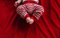 Closeup of white chubby baby legs feet. Child infant lying on red bed in clothes barefoot. Top view Royalty Free Stock Photo