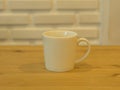 Closeup White Cofee Cup on the wooden table with White Brick wall background. Royalty Free Stock Photo