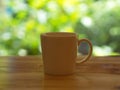 Closeup White Cofee Cup on the wooden table with a green leaf bokeh. Royalty Free Stock Photo