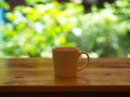 Closeup White Cofee Cup on the wooden table with a green leaf bokeh. Royalty Free Stock Photo