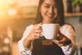 Closeup of white coffee cup with beautiful Asian woman barista background for serving to customer. Job and occupation. Food and Royalty Free Stock Photo