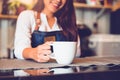 Closeup of white coffee cup with beautiful Asian woman barista background for serving to customer. Job and occupation. Food and Royalty Free Stock Photo