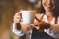 Closeup of white coffee cup with beautiful Asian woman barista background for serving to customer. Job and occupation. Food and Royalty Free Stock Photo