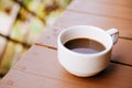 Closeup of white coffee cup with hot coffee on wood Table