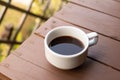 Closeup of white coffee cup with hot coffee on wood Table