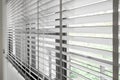 Closeup white color wooden blind with white ladder tape curtains.Sunlight through the windows in the city with garden.Selective fo