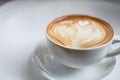 Closeup of white cup of hot coffee latte with milk foam heart shape art with dirty lip marks on white table Royalty Free Stock Photo