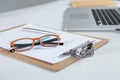 Closeup of white desktop with laptop, glasses, coffee cup, notepads and other items on blurry city background Royalty Free Stock Photo