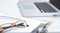 Closeup of white desktop with laptop, glasses, coffee cup, notepads and other items on blurry city background Royalty Free Stock Photo