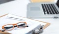 Closeup of white desktop with laptop, glasses, coffee cup, notepads and other items on blurry city background Royalty Free Stock Photo