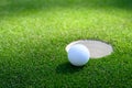 Closeup of white golf ball next to the cup on a putting green Royalty Free Stock Photo