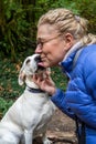 Closeup of white lab mix dog, collar and dog tags, giving a dog kiss to a blond woman