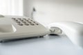 Closeup of white landline telephone with handset off the hook Royalty Free Stock Photo