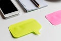 Closeup of white office desk, two colored stickers for notes, smartphone, notebook and metallic pen, business mockup Royalty Free Stock Photo