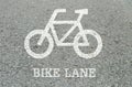 Closeup white painted of bicycle sign in bike lane at the street floor in park textured background