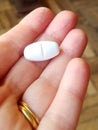 Closeup of white pill in hand