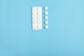 Closeup of white pills and blister on a blue background. Heap of pills - medical background