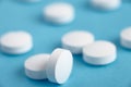 Closeup of white pills on a blue background. Heap of pills - medical background