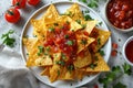 closeup of a white plate of delicious crispy nachos with hot sauce top view