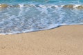 Closeup of a white sea foam on a yellow coastal sand on a sunny day. Marine background and copy space Royalty Free Stock Photo