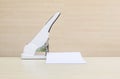 Closeup white stapler with white work paper , office equipment on blurred wood desk and wall in office room textured background un Royalty Free Stock Photo