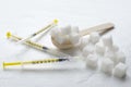 Closeup of white sugar, insulin syringes and wooden spoon ful of sugar cubes on the white surface