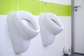 Closeup of white urinals in men`s bathroom, design of white ceramic urinals for men in toilet room. Royalty Free Stock Photo