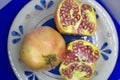 Closeup of whole and cut pomegranate on light blue plate Royalty Free Stock Photo