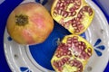Closeup of whole and cut pomegranate on light blue plate Royalty Free Stock Photo