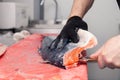 Closeup whole fresh salmon fish preparing fillet with knife on red cutting board in professional kitchen of restaurant. Concept Royalty Free Stock Photo