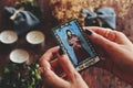 Closeup of wiccan witch holding a small hand painted made up Hermit tarot card in her hands.