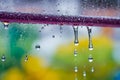 Closeup through window of rainy day with water dripping down glass against blurred colorful background Royalty Free Stock Photo