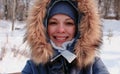 Closeup winter portrait of young smiling woman in blue cap and fur hood. Royalty Free Stock Photo