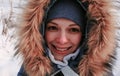 Closeup winter portrait of young smiling woman in blue cap and fur hood. Royalty Free Stock Photo