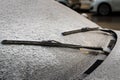 Closeup of wipers and frosted car windshield covered with ice and snow. Winter weather