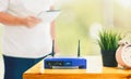 Closeup of a wireless router and a man using smartphone on living room at home ofiice Royalty Free Stock Photo
