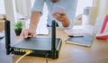 Closeup of a wireless router and a man using smartphone on living room at home ofiice, equipment for  working from home, while in Royalty Free Stock Photo