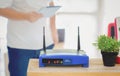 Closeup of a wireless router and a man using smartphone on living room at home ofiice, equipment for  working from home, while in Royalty Free Stock Photo