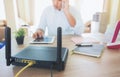 Closeup of a wireless router and a man using smartphone on living room at home ofiice, equipment for  working from home, while in Royalty Free Stock Photo