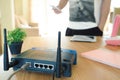 Closeup of a wireless router and a young man using a smartphone on living room at home with a window in the background Royalty Free Stock Photo