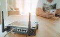 Closeup of a wireless router and a young man using a smartphone on living room at home with a window in the background Royalty Free Stock Photo