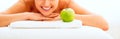 Closeup on woman with apple laying on massage tabl