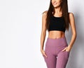 Closeup of woman athletic body in sportswear pants and crop top sports bra on gray