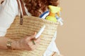 Closeup on woman on beige background with straw bag and hygienic lipstick